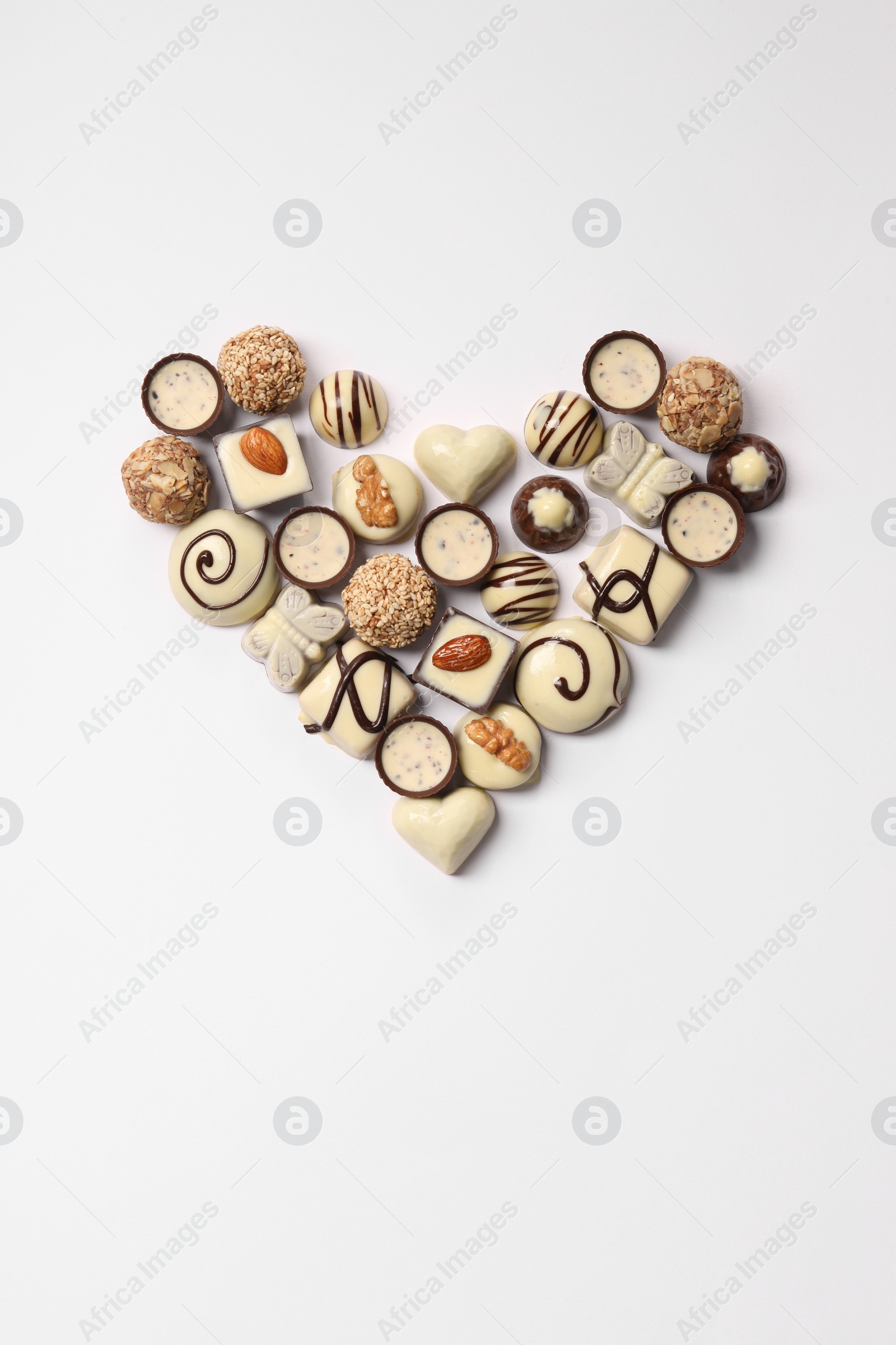 Photo of Heart made with delicious chocolate candies on white background, top view