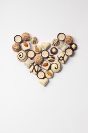 Photo of Heart made with delicious chocolate candies on white background, top view