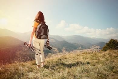 Photo of Professional photographer with modern camera and tripod in mountains, back view. Space for text