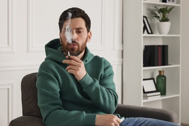 Photo of Man using cigarette holder for smoking indoors