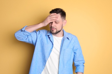 Man suffering from headache on color background