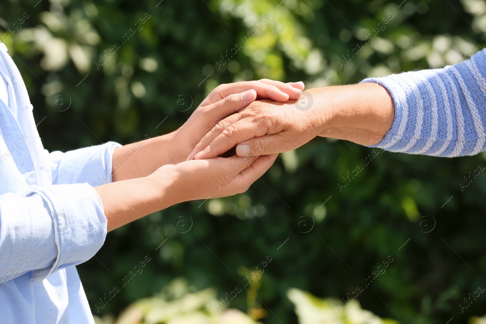 Photo of Helping hands on blurred background, closeup. Elderly care concept