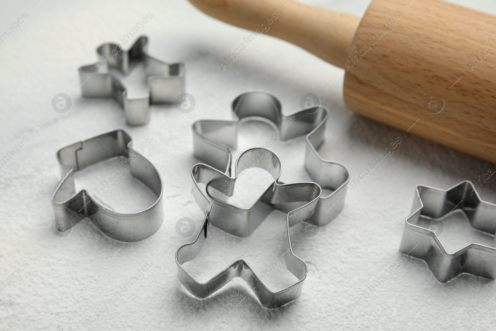 Photo of Cookie cutters, rolling pin and flour on white table, closeup
