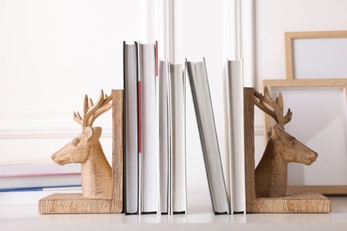 Wooden deer shaped bookends with books on table indoors