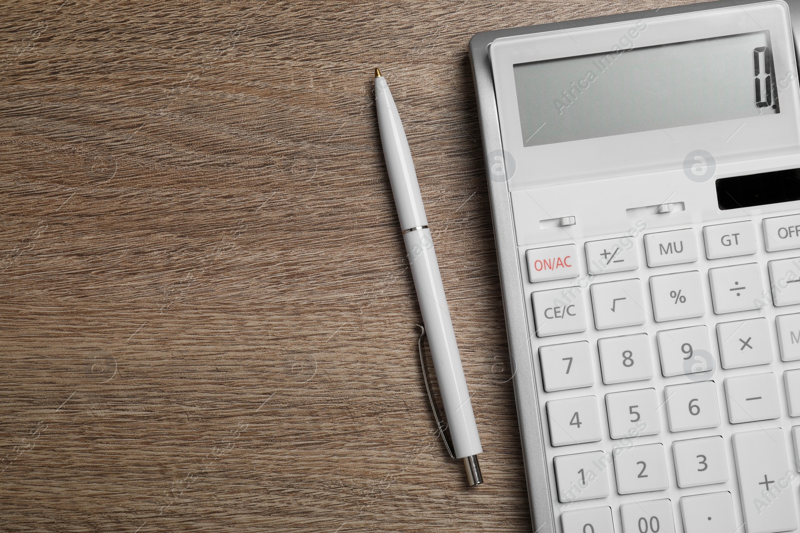 Photo of Calculator and pen on wooden table, top view. Space for text