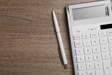 Photo of Calculator and pen on wooden table, top view. Space for text