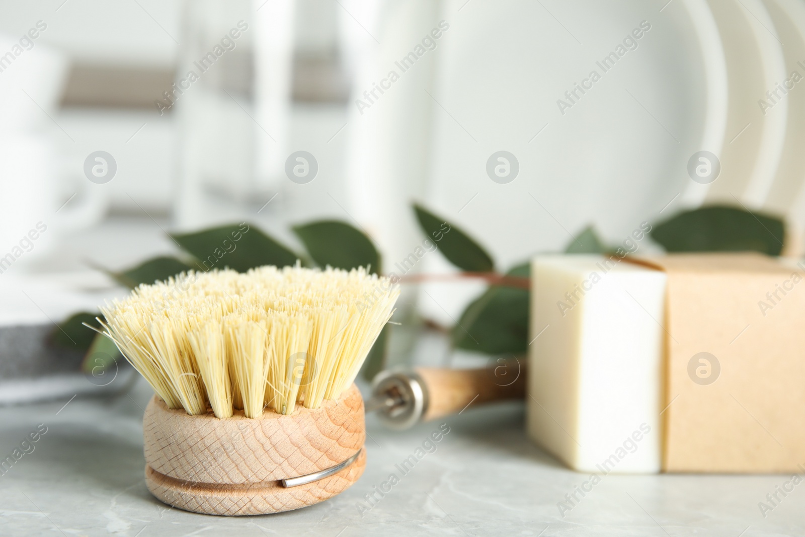 Photo of Cleaning brush and soap bar for dish washing on grey marble table, closeup