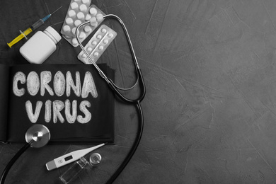 Photo of Notepad with words CORONA VIRUS, stethoscope and medicines on grey stone background, flat lay. Space for text