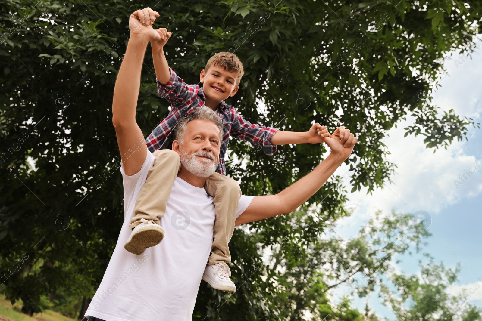 Photo of Cute little boy and grandfather spending time together in park