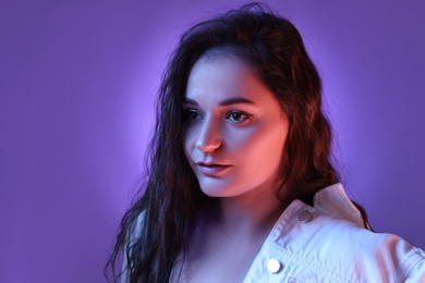 Portrait of beautiful young woman on color background with neon lights