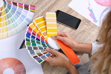 Photo of Woman with color palette samples at table, closeup