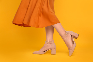 Photo of Woman wearing stylish shoes on yellow background, closeup