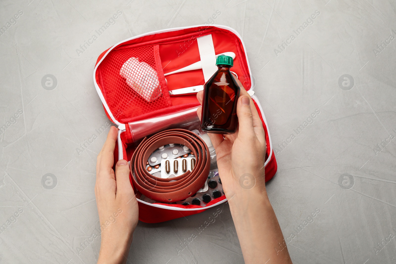 Photo of Woman taking medical alcohol from first aid kit at grey table, top view