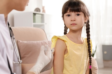 Family doctor vaccinating little child at home