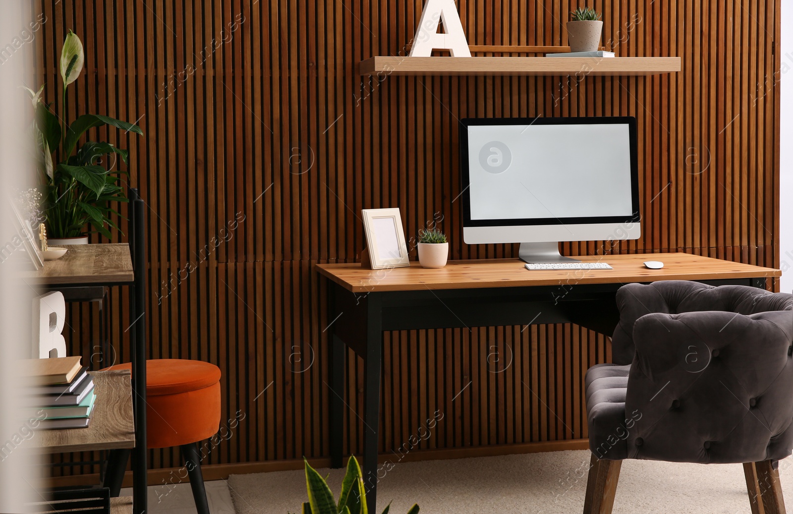 Photo of Comfortable workplace with computer near wooden wall in stylish room interior. Home office design