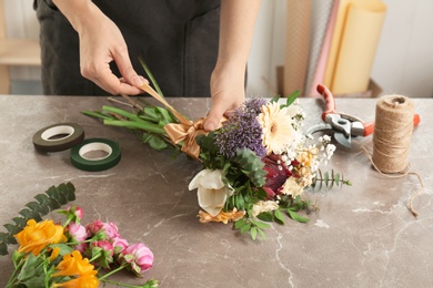 Female florist making beautiful bouquet at table