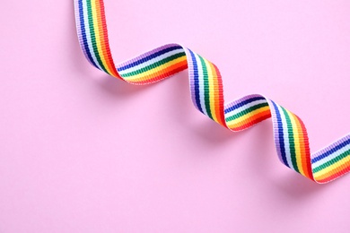 Photo of Bright rainbow ribbon on color background, top view with space for text. Symbol of gay community