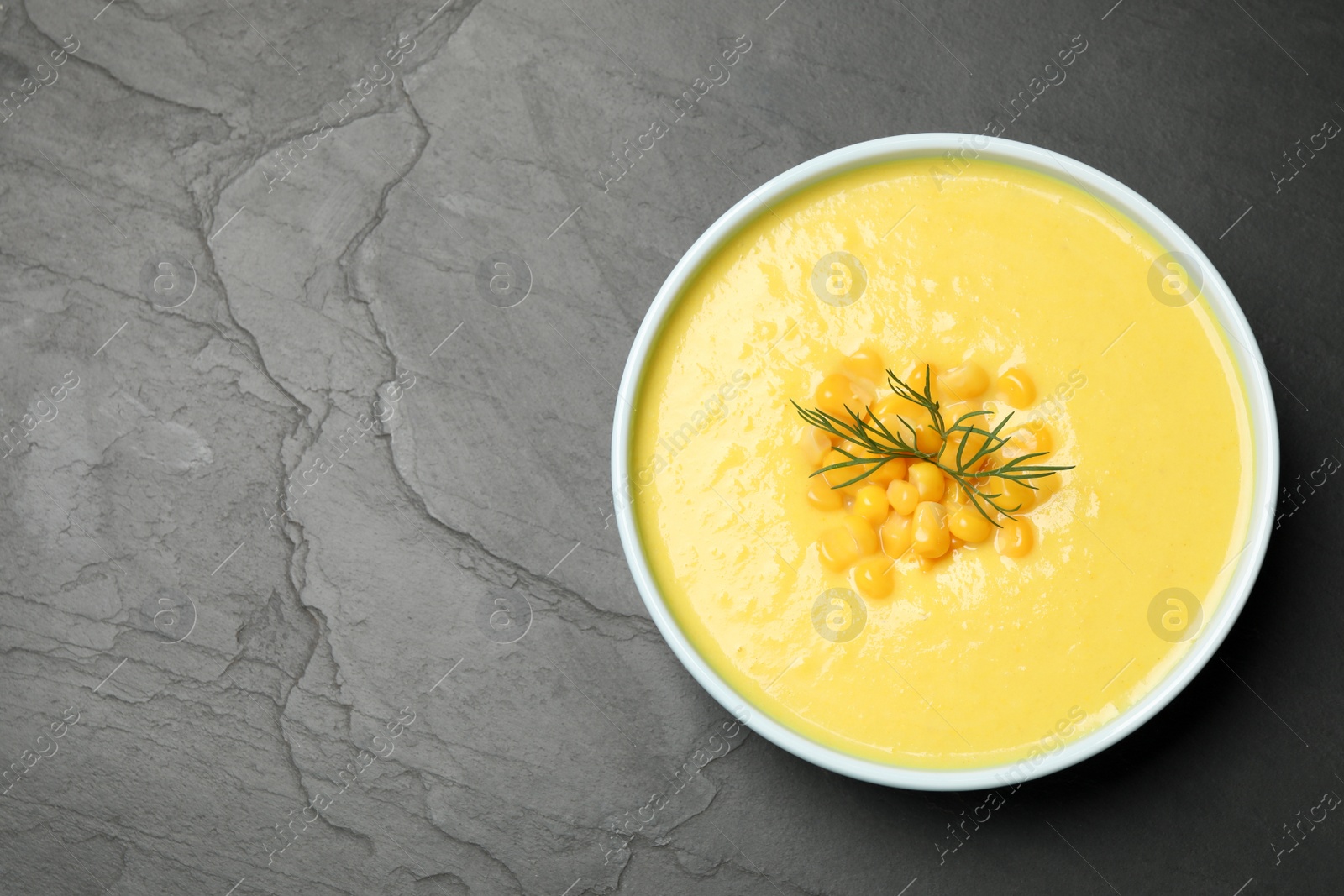 Photo of Delicious creamy corn soup on black table, top view. Space for text