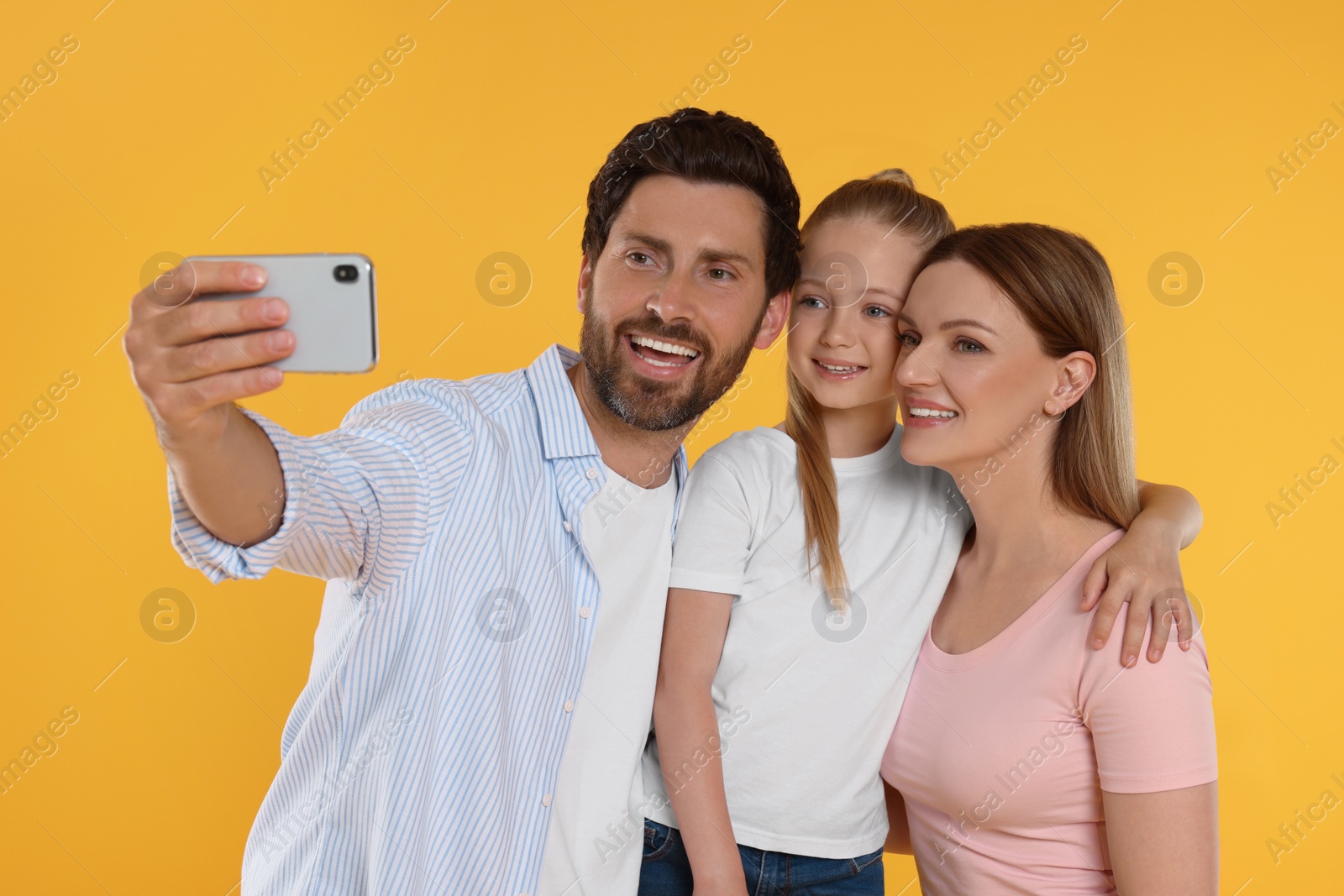 Photo of Happy family taking selfie on orange background