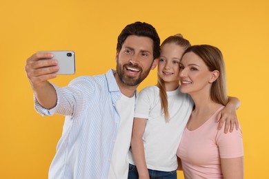 Photo of Happy family taking selfie on orange background