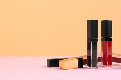 Photo of Many different lip glosses on color background, space for text