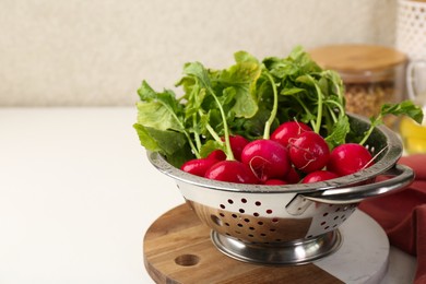 Wet radish in colander on white table, closeup. Space for text