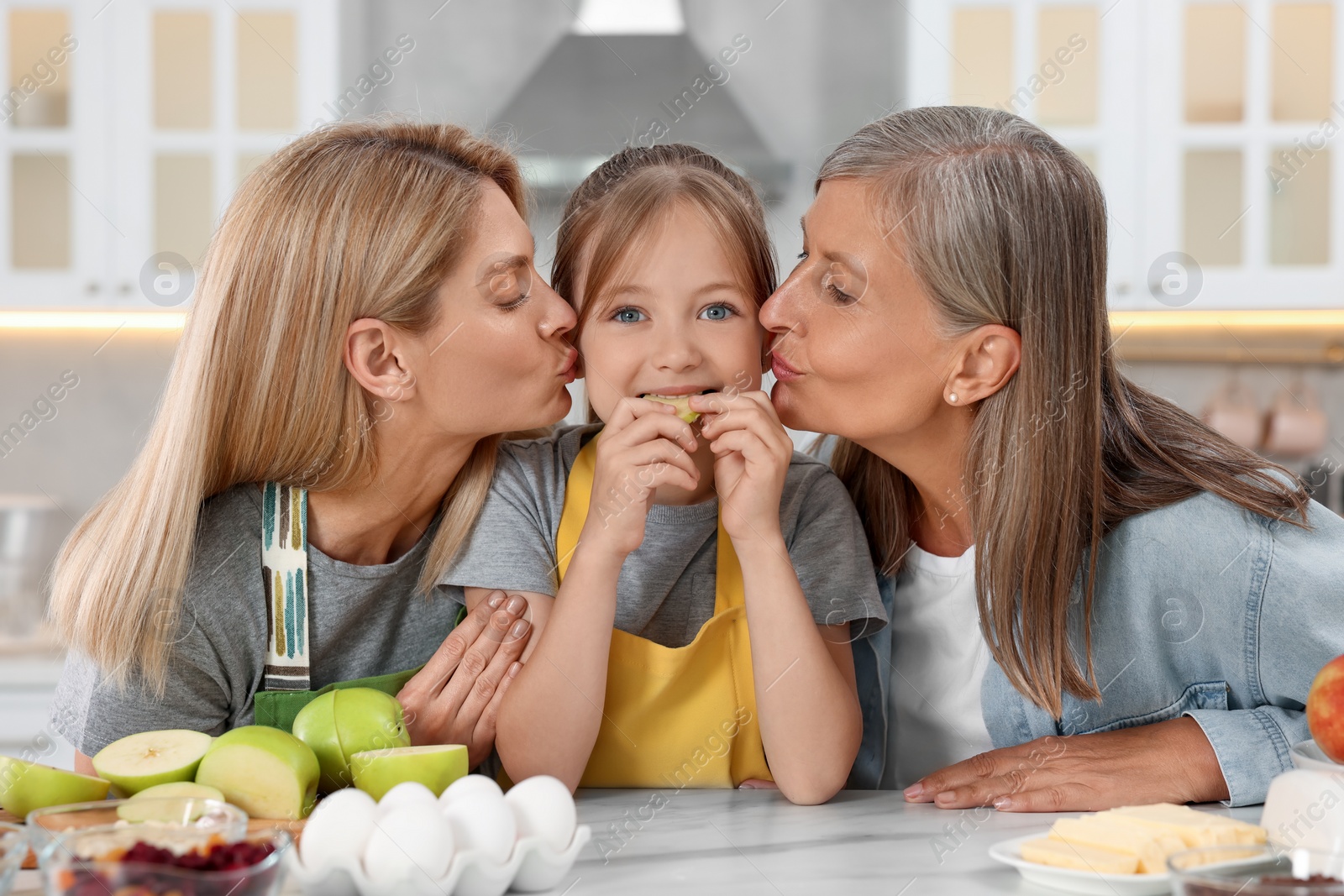 Photo of Three generations. Grandmother, her daughter and granddaughter in kitchen