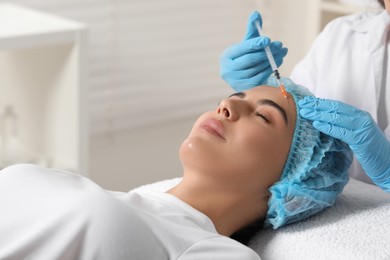 Photo of Doctor giving facial injection to young woman in clinic. Cosmetic surgery