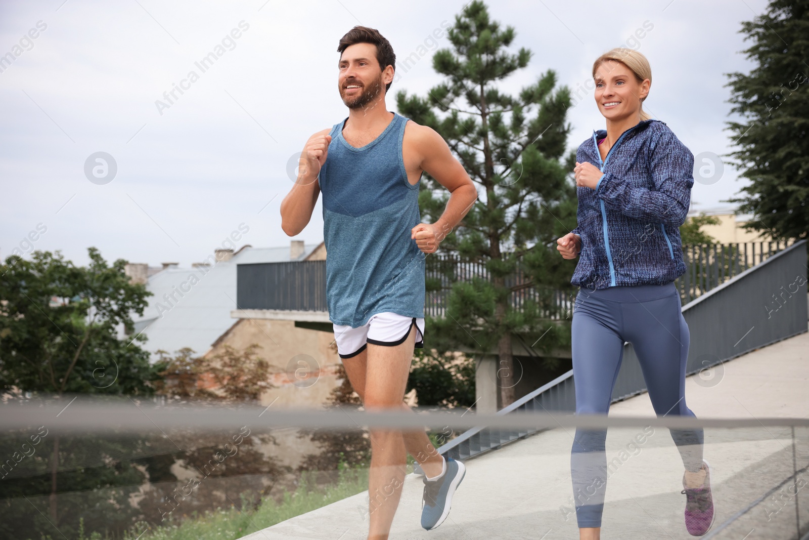 Photo of Healthy lifestyle. Happy sporty couple running outdoors, space for text