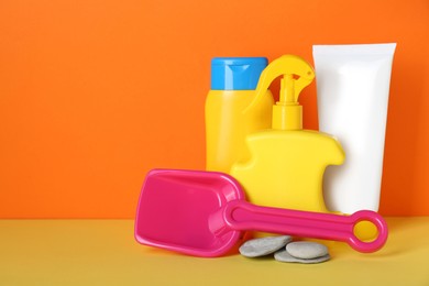Photo of Different suntan products, stones and plastic beach toy on color background. Space for text