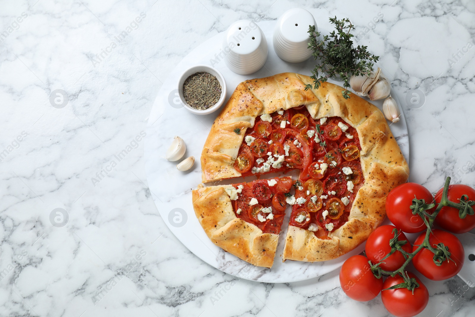 Photo of Tasty galette with tomato, thyme and cheese (Caprese galette) served on white marble table, top view. Space for text