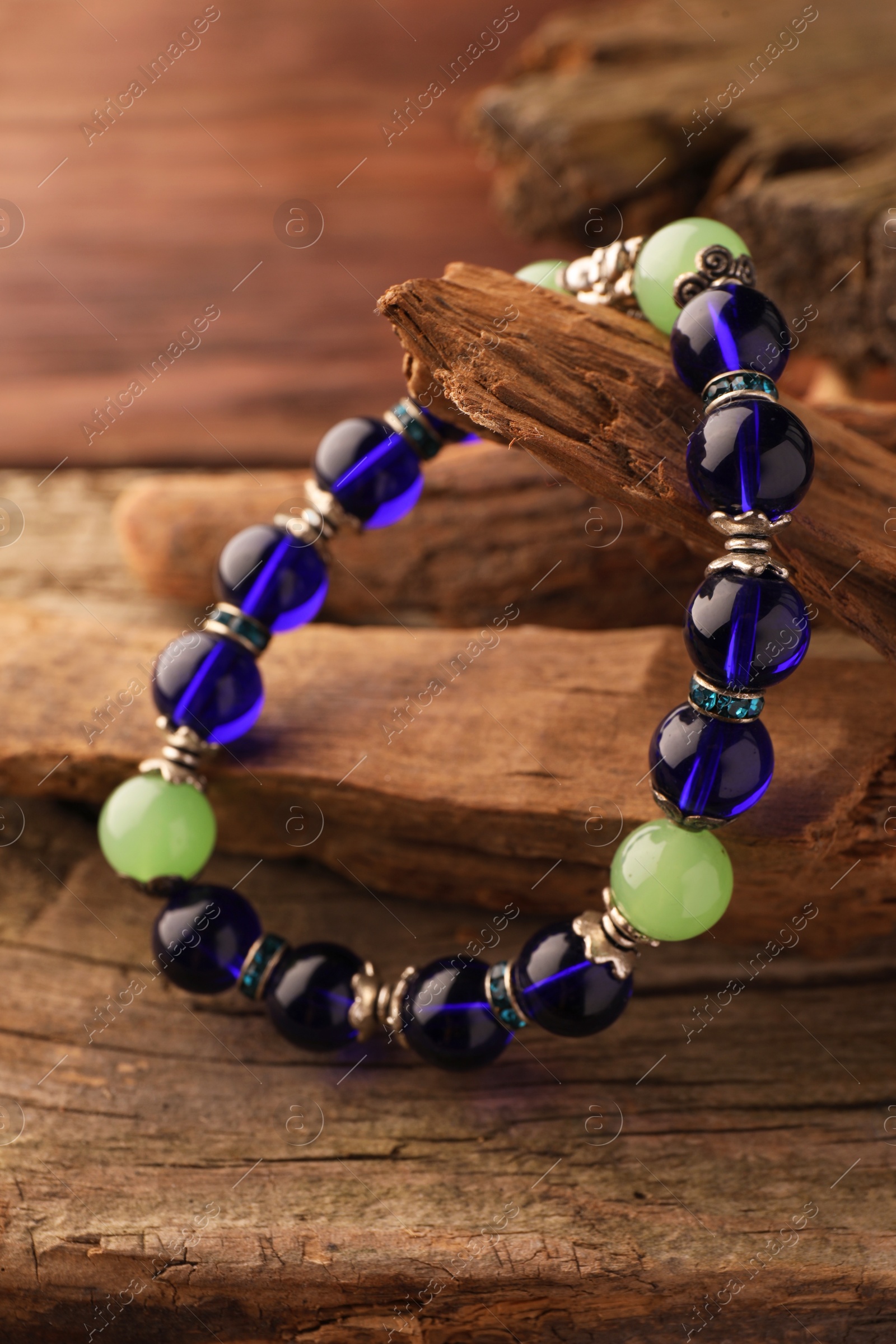 Photo of Stylish presentation of beautiful bracelet with gemstones on wooden table, closeup