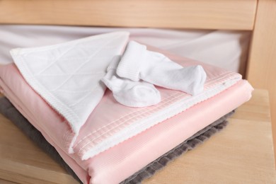 Photo of Soft blanket and baby socks on wooden table, closeup