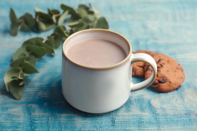 Cup with hot cocoa drink and cookies on wooden table