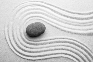 Photo of Grey stone on sand with pattern, top view. Zen, meditation, harmony