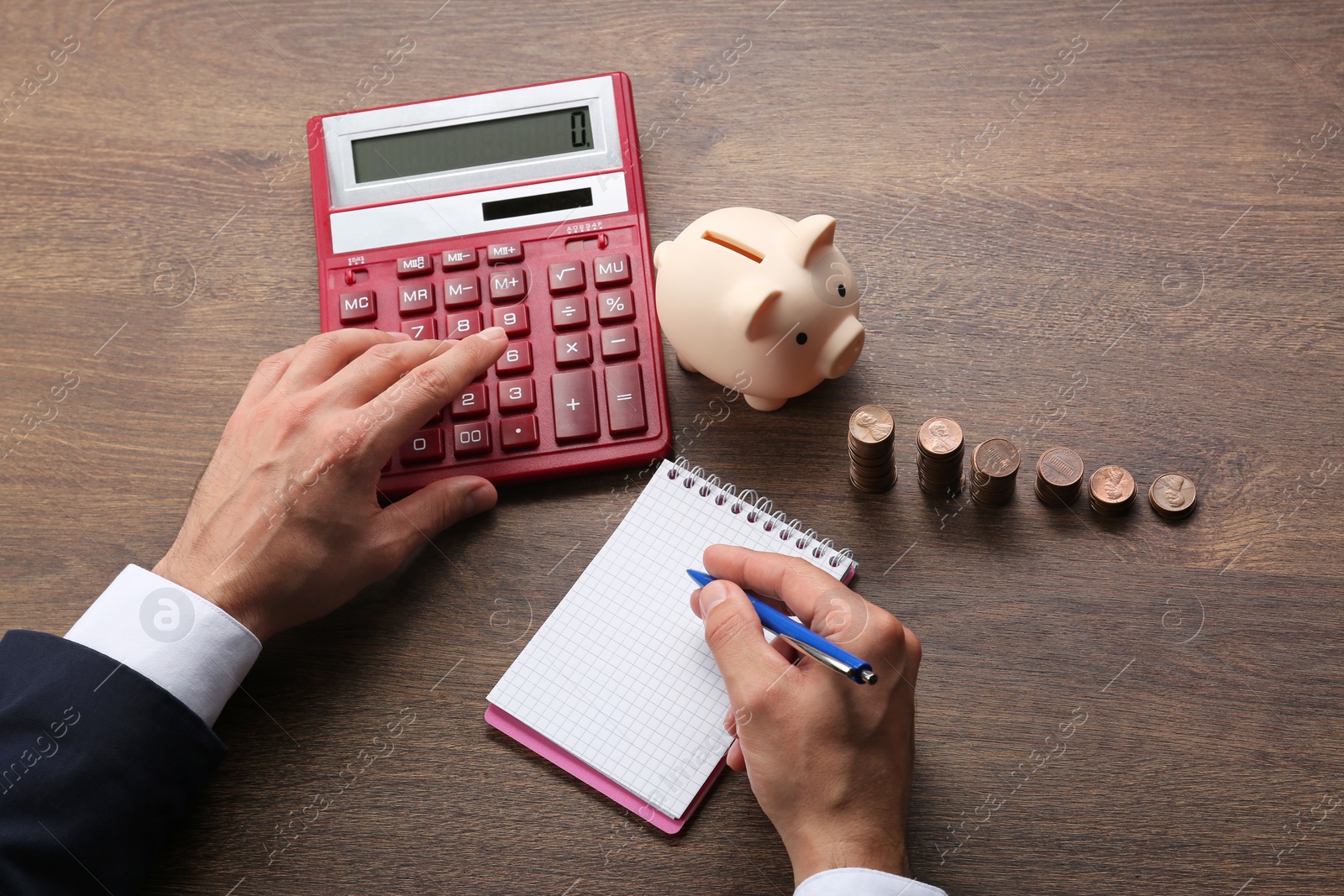 Photo of Budget planning. Businessman with notebook calculating at wooden table, above view