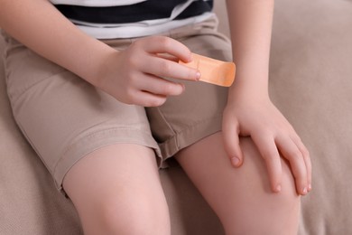 Photo of Little boy with sticking tape on sofa, closeup