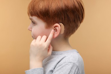 Photo of Little boy with hearing aid on pale brown background