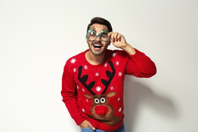 Photo of Young man in Christmas sweater with party glasses on white background