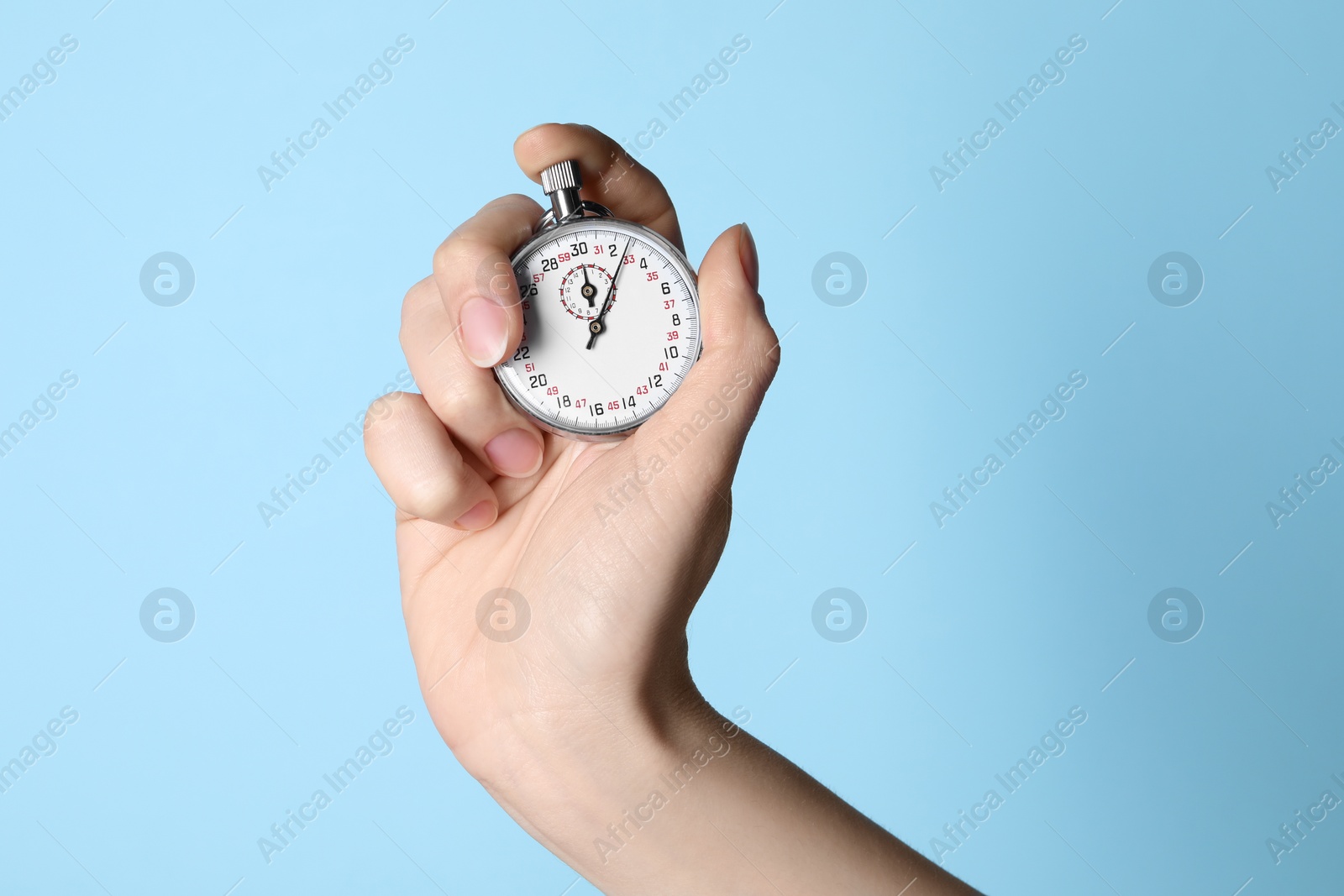 Photo of Woman holding vintage timer on light blue background, closeup