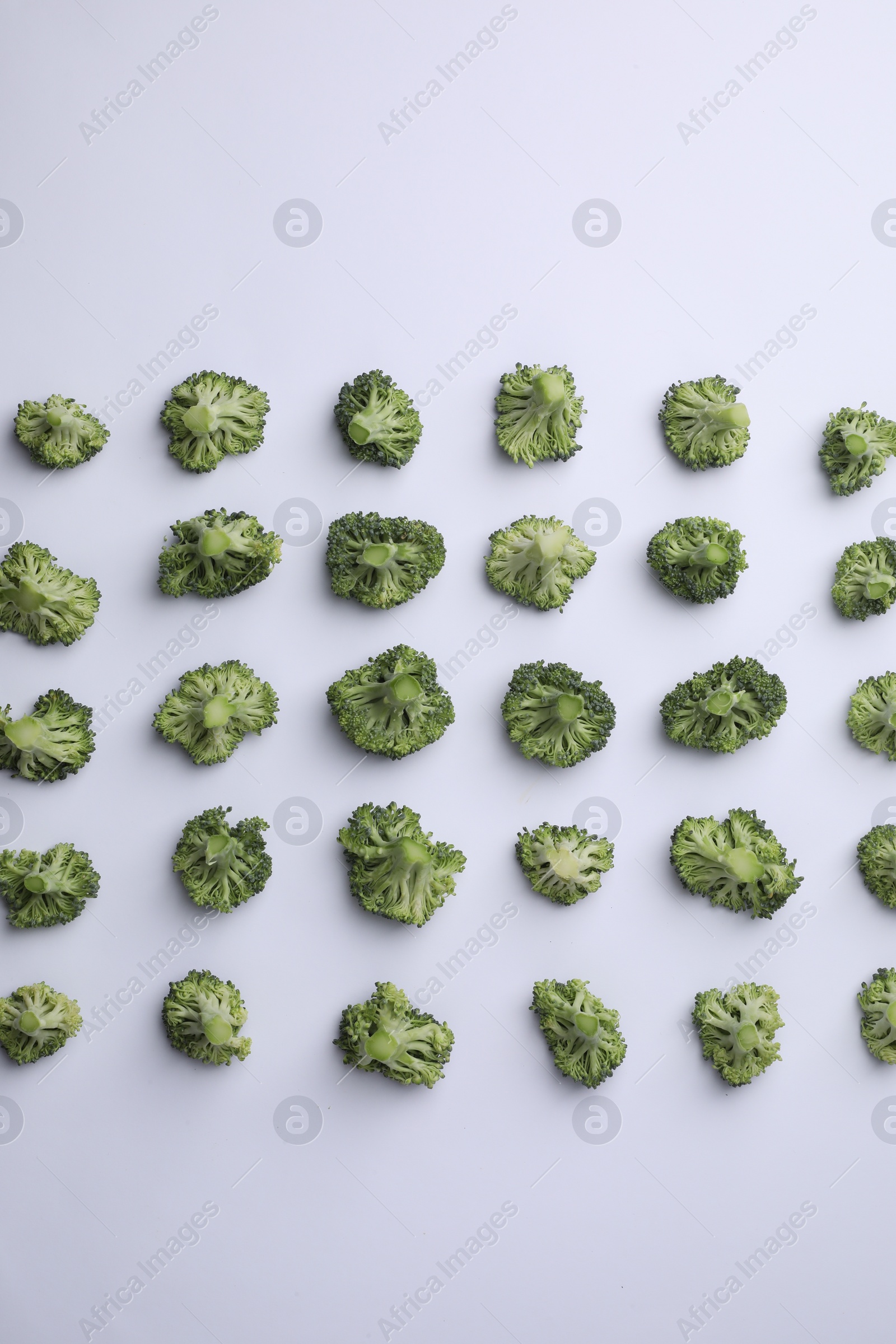 Photo of Many fresh green broccoli pieces on white background, flat lay