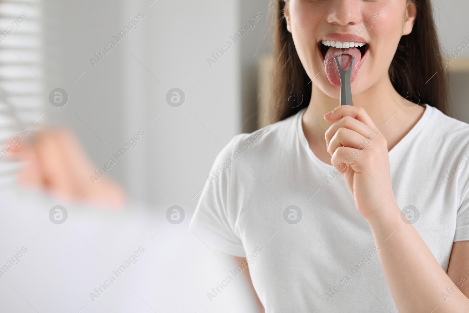 Photo of Woman brushing her tongue with cleaner indoors, closeup. Space for text