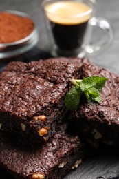 Photo of Delicious chocolate brownies with nuts and fresh mint on slate, closeup