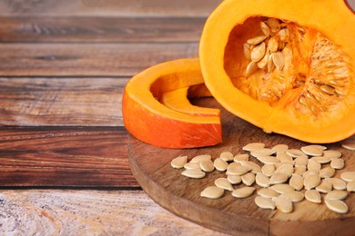 Photo of Fresh pumpkin and vegetable seeds on wooden table, closeup. Space for text