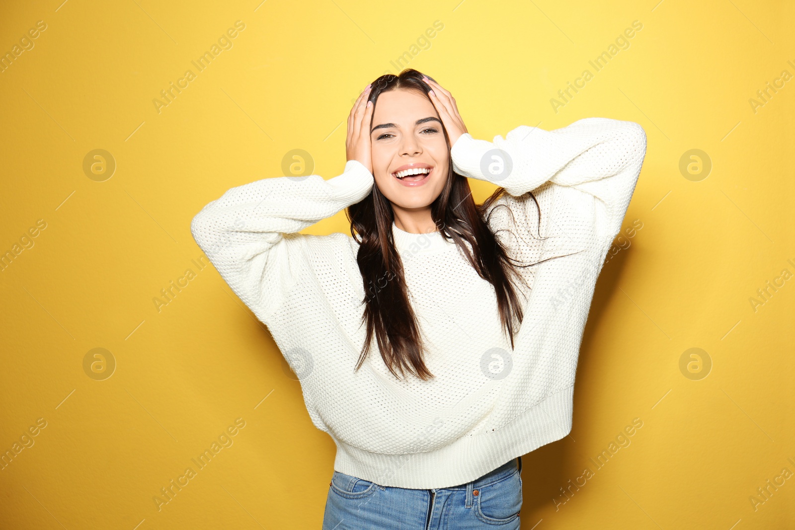 Image of Happy young woman wearing warm sweater on yellow background 