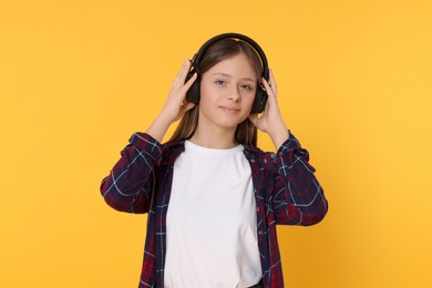 Photo of Teenage girl listening to music with headphones on orange background