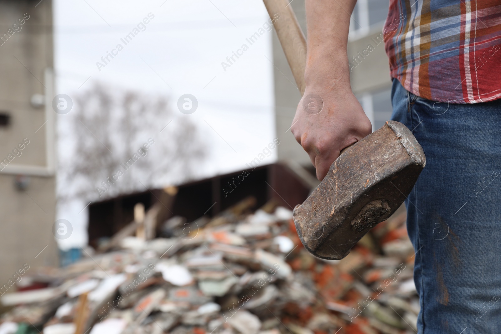 Photo of Man with sledgehammer near pile of broken stones outdoors, closeup. Space for text