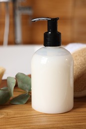 Dispenser of liquid soap and eucalyptus branch on wooden table