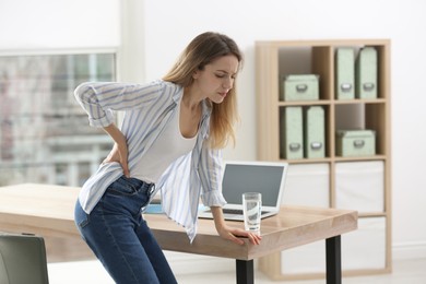 Woman suffering from back pain in office. Symptom of bad posture