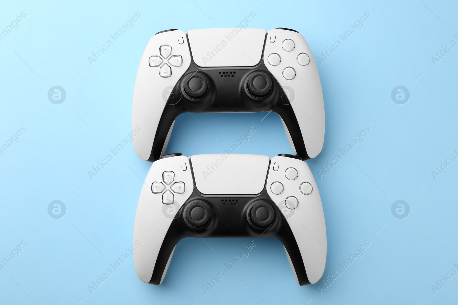 Photo of Wireless game controllers on light blue background, flat lay